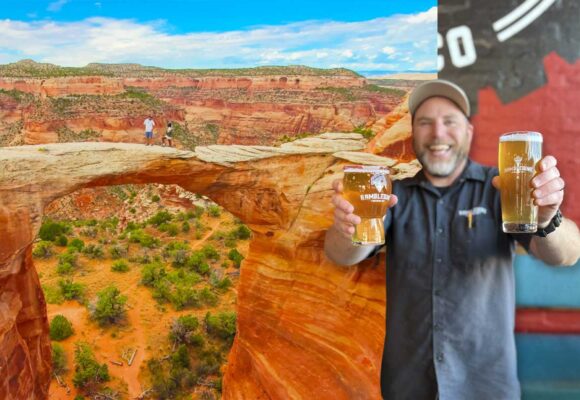 Brewer holding beers with red rock arch landscape in background
